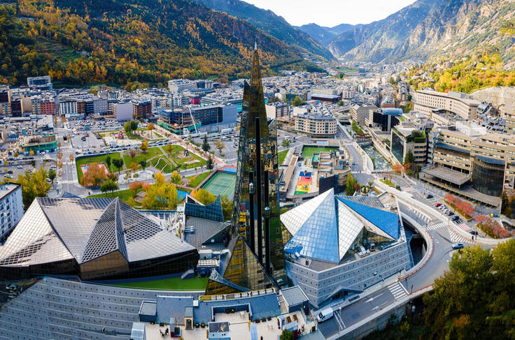 Aerial view of futuristic buildings and mountains in Andorra la Vella, under a clear sky.