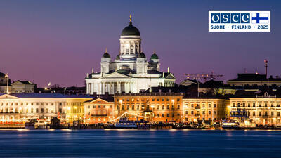 Helsinki Cathedral lit up at dusk, reflecting on the waterfront, under a purple sky.